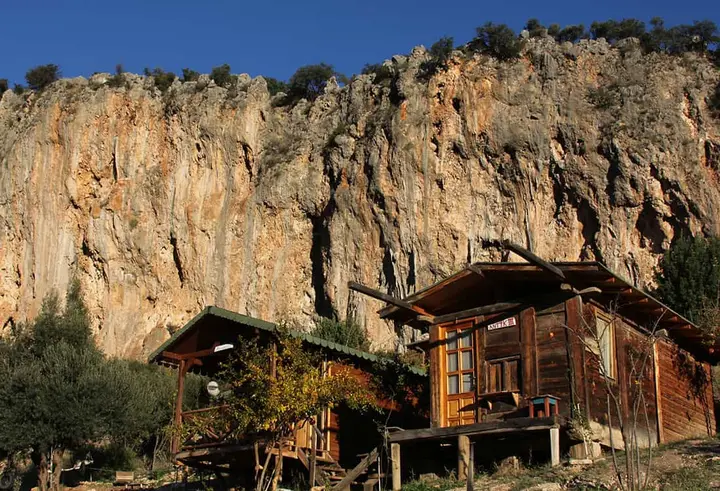 Yüksek turuncu kireçtaşı duvarın altında iki bungalov