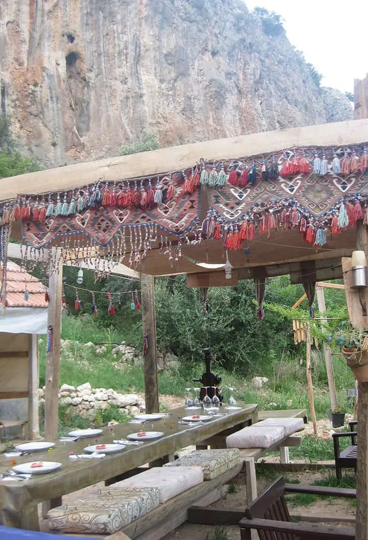 Camp dining area with a tasselled textile canopy and a long table