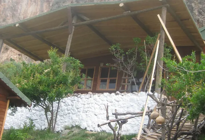 Wooden building above a whitewashed stone wall with a fruit tree