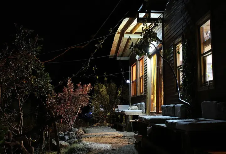 Wooden building at night with lit windows and a stone path