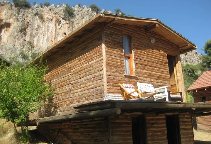 Seitenansicht des Bungalows Nar mit Terrasse und Felswand dahinter