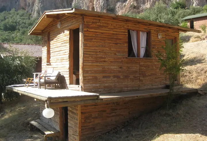 Holzbungalow Nar mit Terrasse und Stühlen unter der Felswand