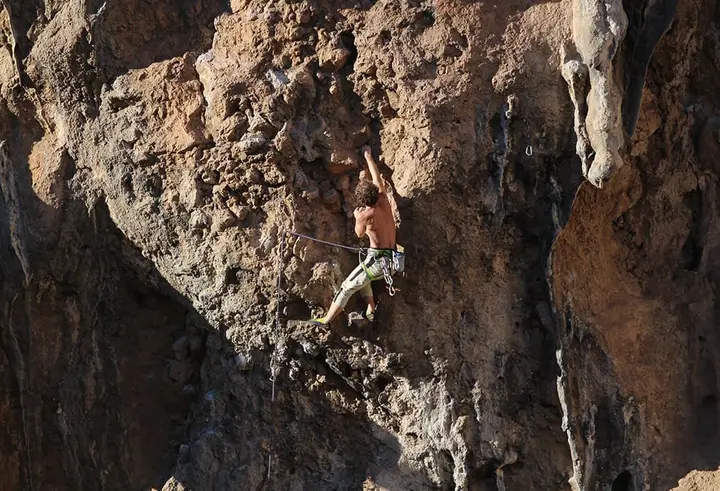 Climber in the middle of a dark orange wall