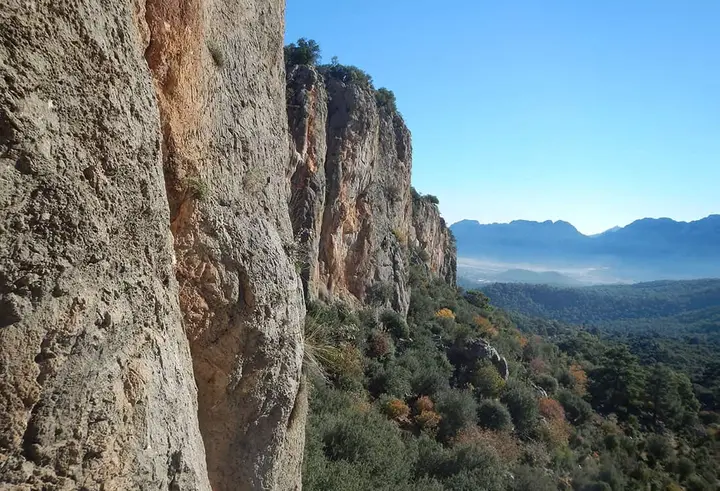 Orange limestone cliff above a forested valley in Geyikbayırı