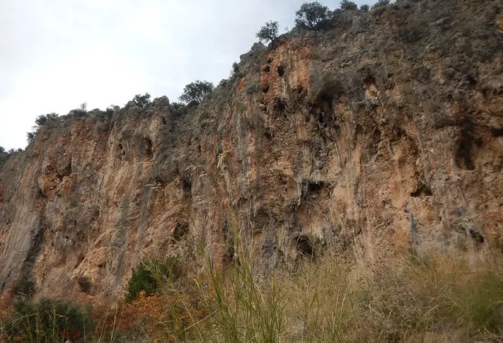 Rugged limestone cliff with brown and orange streaks