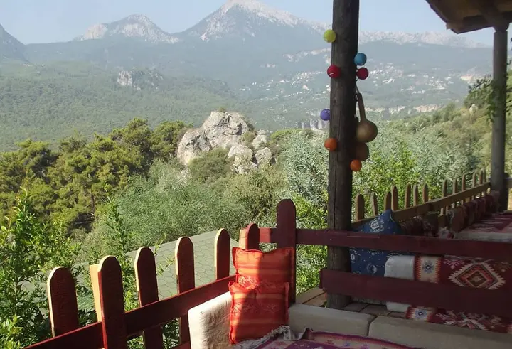 Wooden terrace railing with a view of rocky mountains and colourful cushions