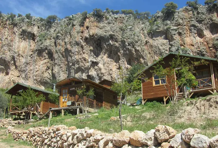 Bungalows am Hang unter einer Kalksteinwand hinter einer Steinmauer