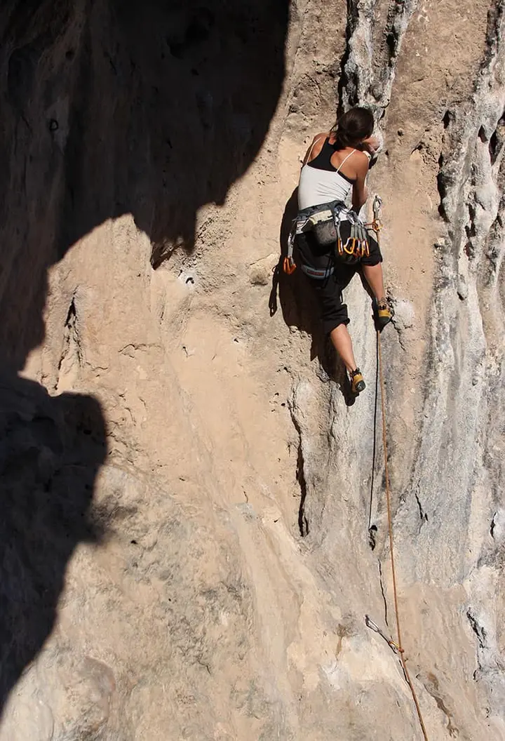 Female climber with gear on a sunlit limestone wall
