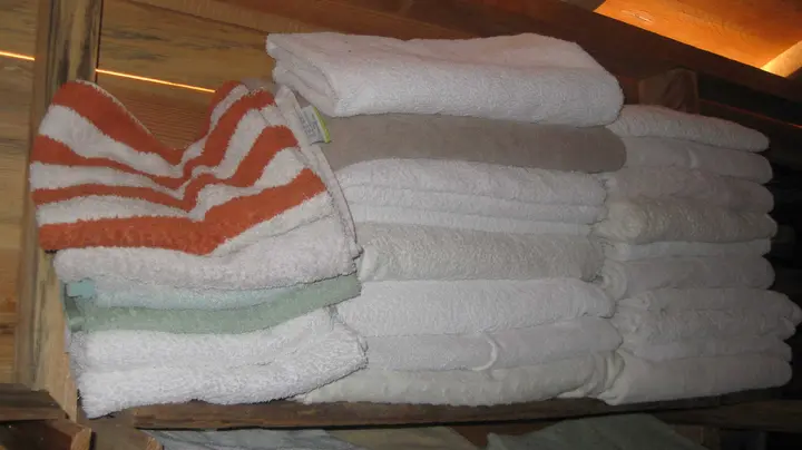 Stack of white and striped towels on a wooden shelf