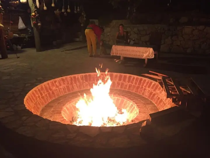 Fire burning in a round brick fire pit at night